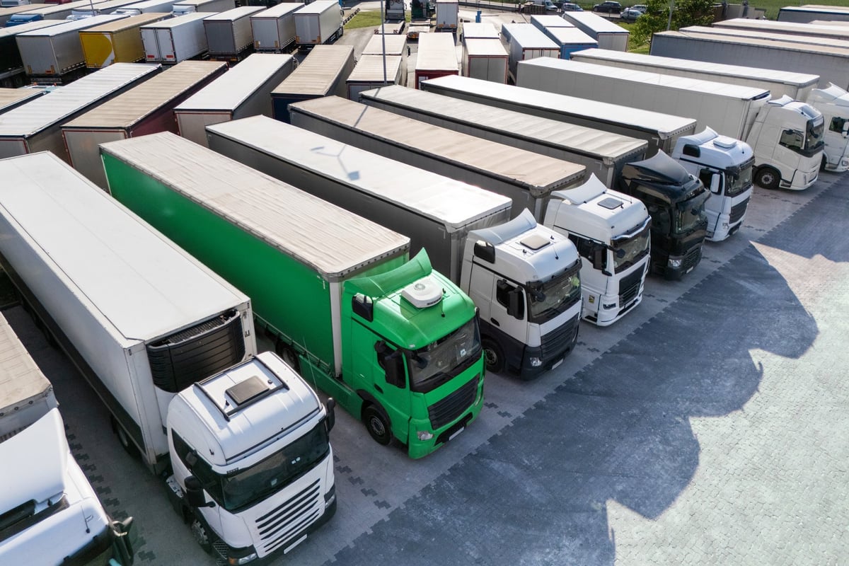 Aerial view of a large truck parking lot at a logistics hub with multiple commercial semi trucks parked in rows
