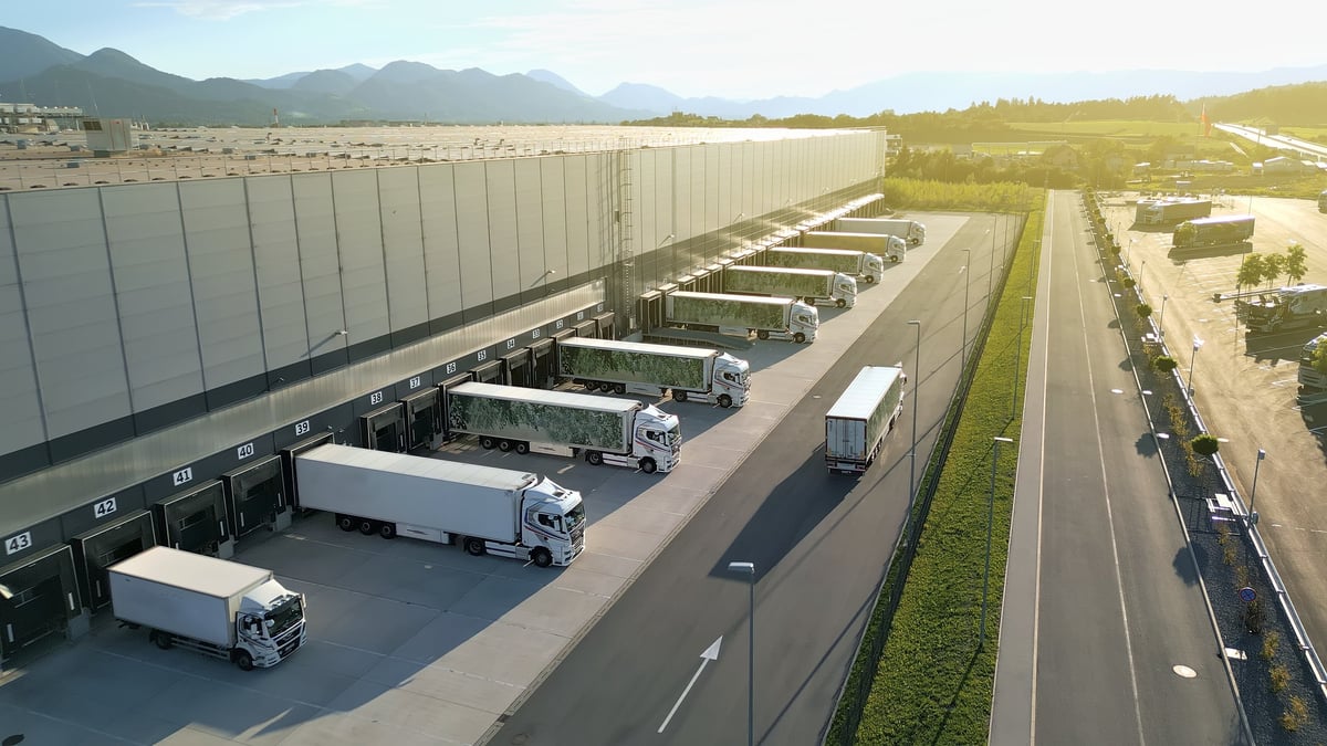 Aerial view of a distribution warehouse with multiple trucks at loading docks and trailer cargo operations