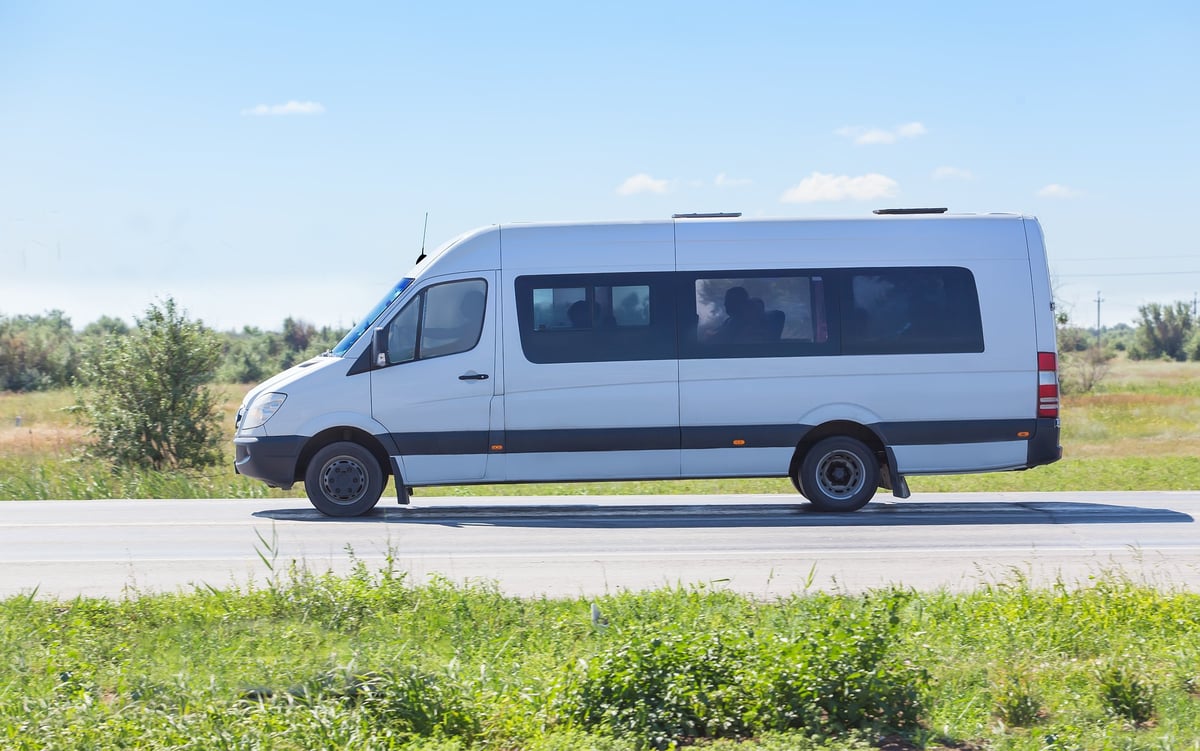 Minibus traveling on a country highway representing personnel transport